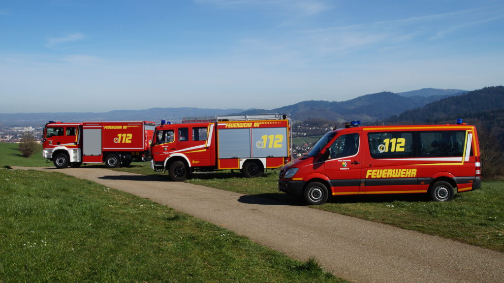 Alle 3 Fahrzeuge der Feuerwehr Au hintereinander auf einer Wiese mit Au im Hintergrund